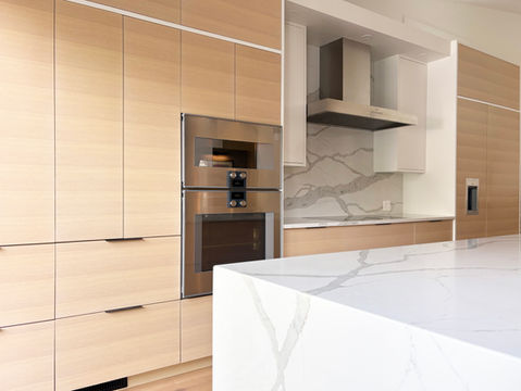 Custom white oak kitchen with flat-panel cabinets, integrated Gaggenau appliances, and a waterfall quartz island – designed by From a Seed Interiors, Ottawa.