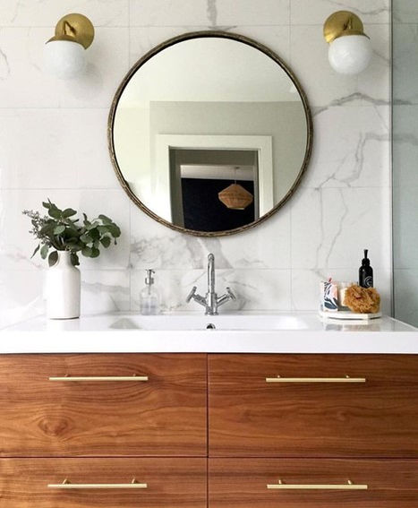 Modern master primary ensuite bathroom design. Porcelain marble feature wall, round brass mirror, brass globe wall sconces, integrated ceramic sink and walnut floating vanity with gold handles. Designed by From a Seed Interiors, Ottawa, ON.
