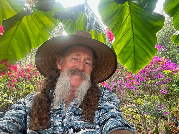 Man with a hat mustache wearing a Hawaii shirt