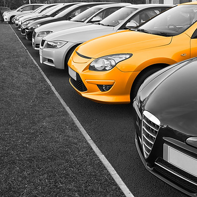 A row of parked cars, mostly in black and white, with one vibrant yellow car standing out.