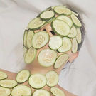 Person covered in cucumber slices during a facial bundle.