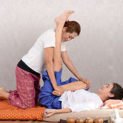 Practitioner performing Thai massage with yoga stretching.