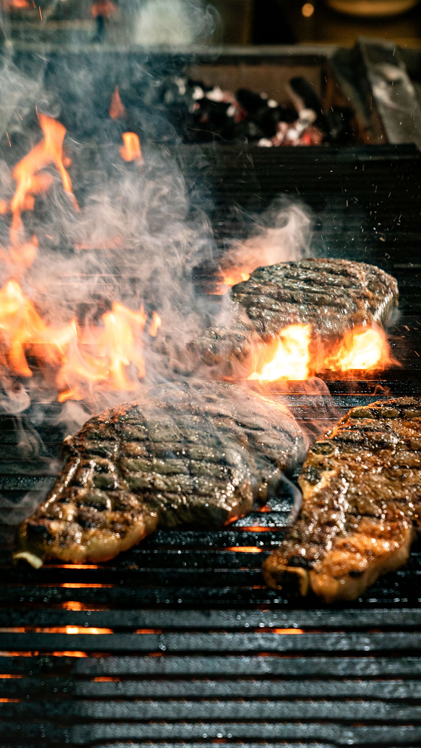 Steaks flaring up over open flame on a conventional grill burner