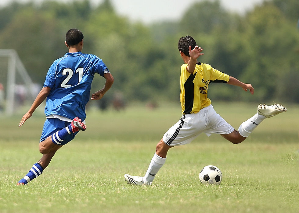 two teenage boys playing soccers for their school teams
