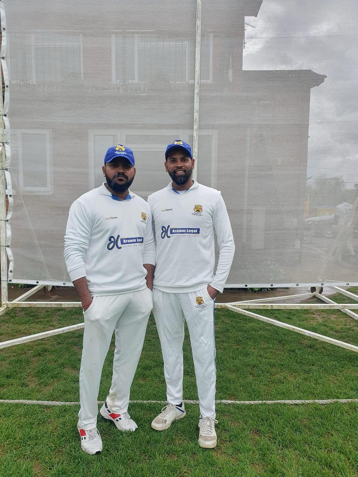 Two men in white cricket uniforms on a field