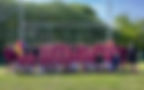 Rugby team in maroon jerseys posing in front of goal posts