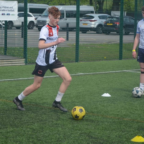 Young man dribbling soccer ball on turf
