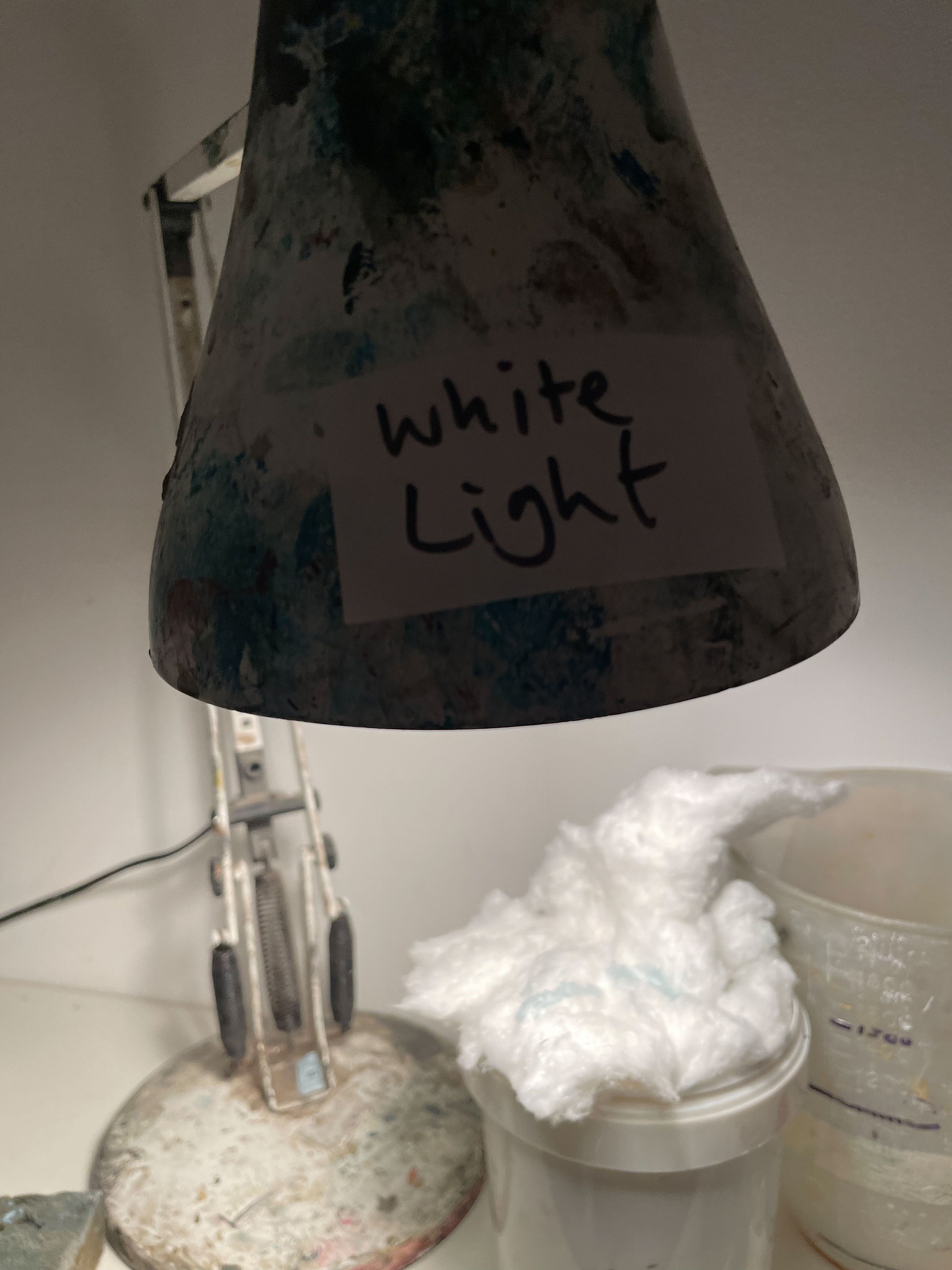 White light in the dark room- a close up of a shade above some cotton wool