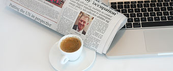 Coffee with newspaper next to keyboard