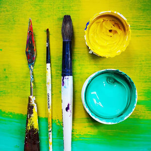 close up of Emily's paint brushes and lids in bright yellow and green