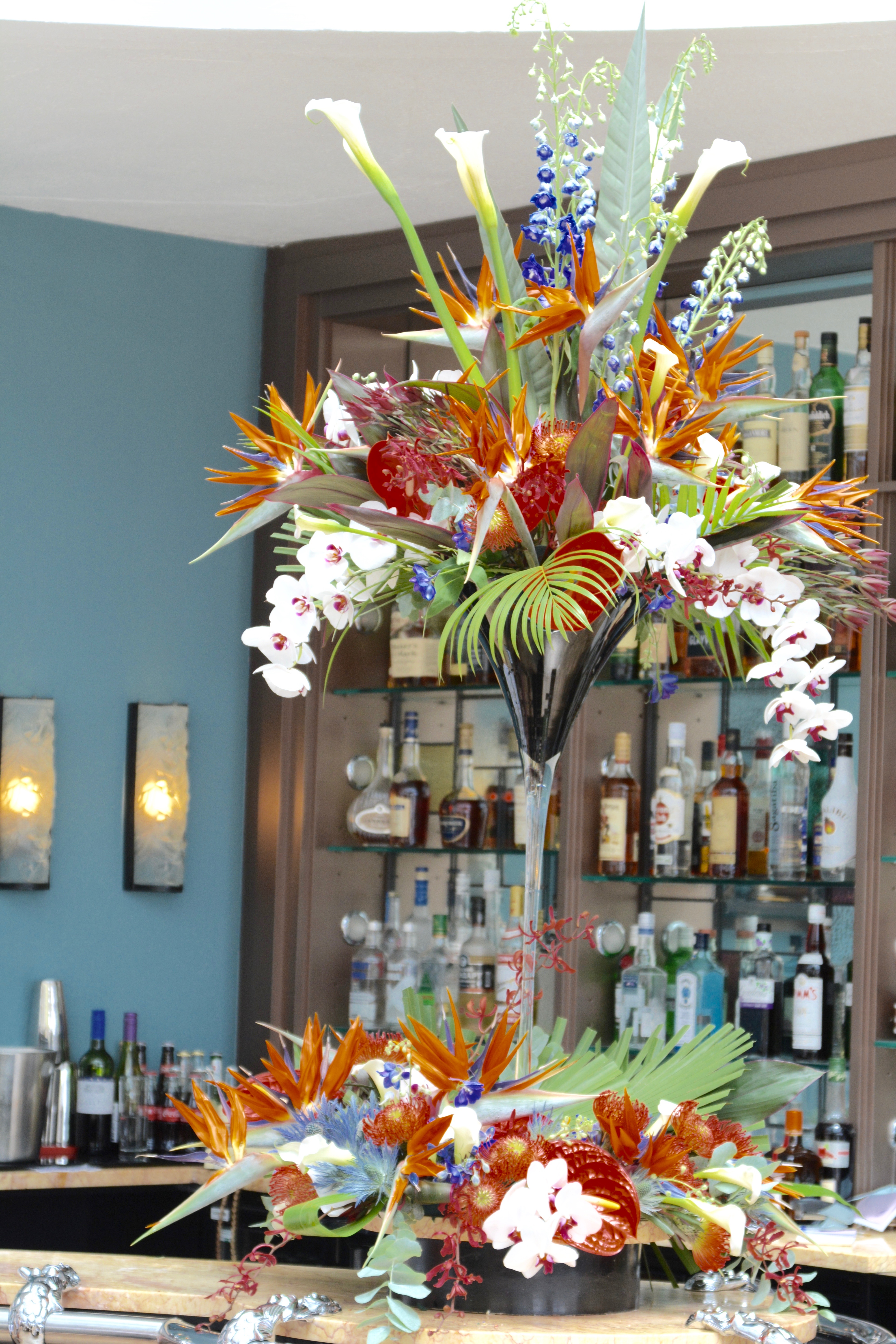 Tropical flowers in tall vase on bar