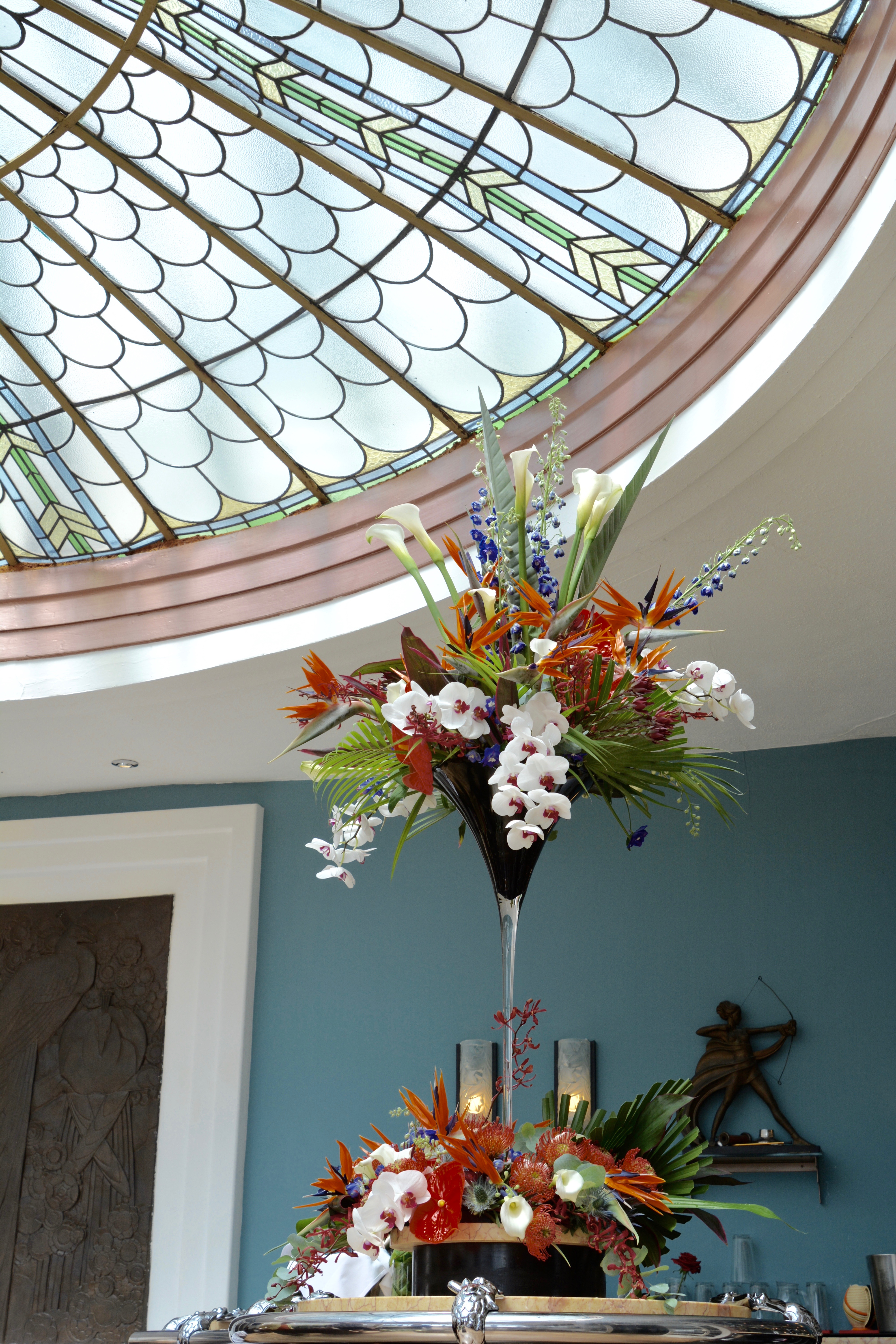 Tropical flowers in tall vase on bar