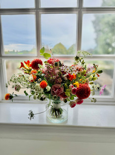 Mixed pink and orange flowers and greenery arranged in a bridal bouquet