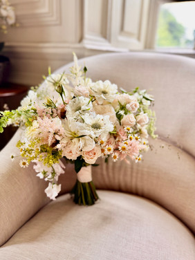 garden style bridal bouquet on a chair beside a window