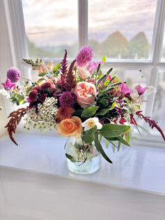 pink, ornage flowers in a vase on a windowsil