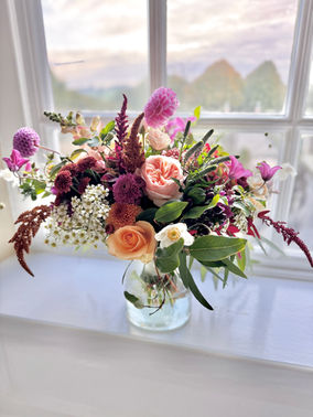 pink, ornage flowers in a vase on a windowsil