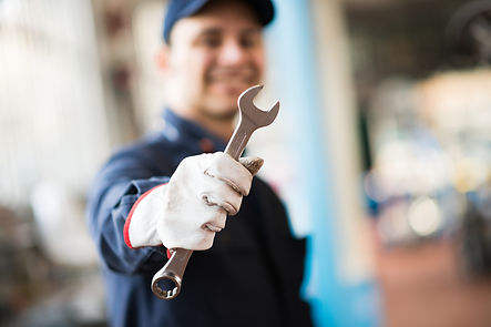 smiling-mechanic-holding-a-wrench-in-his-shop.jpg