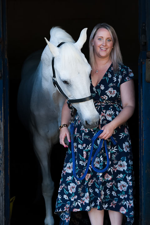 lady stood with her horse in a stable
