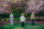 Two men one woman standing under flowering trees meditating