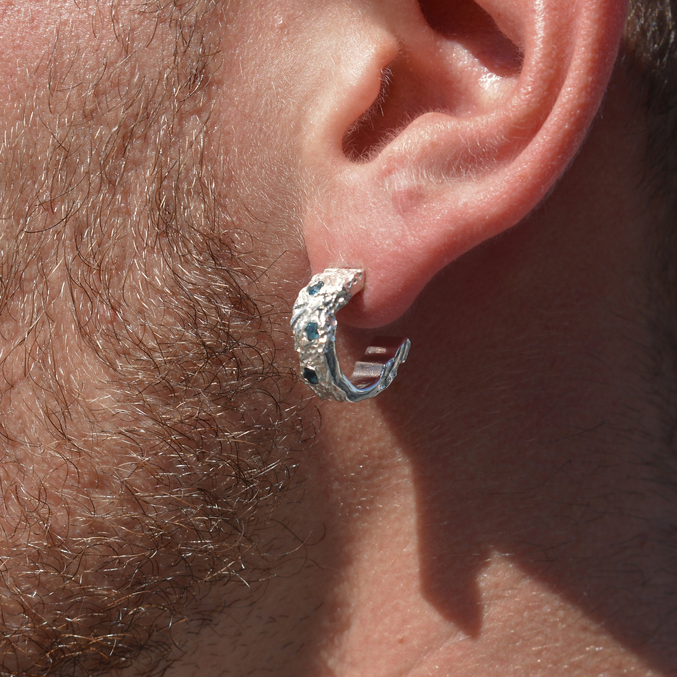 Thumbnail: Close-up photo of handmade sterling silver hoop earring with London Blue Topaz gemstones, featuring a sculptural molten textu