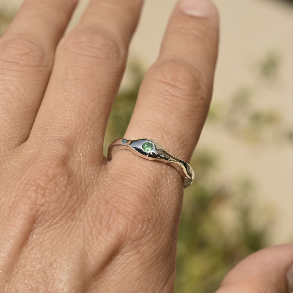 Thumbnail: Sterling silver ring with green emerald set in a wavy, organic band design, photographed on hand.