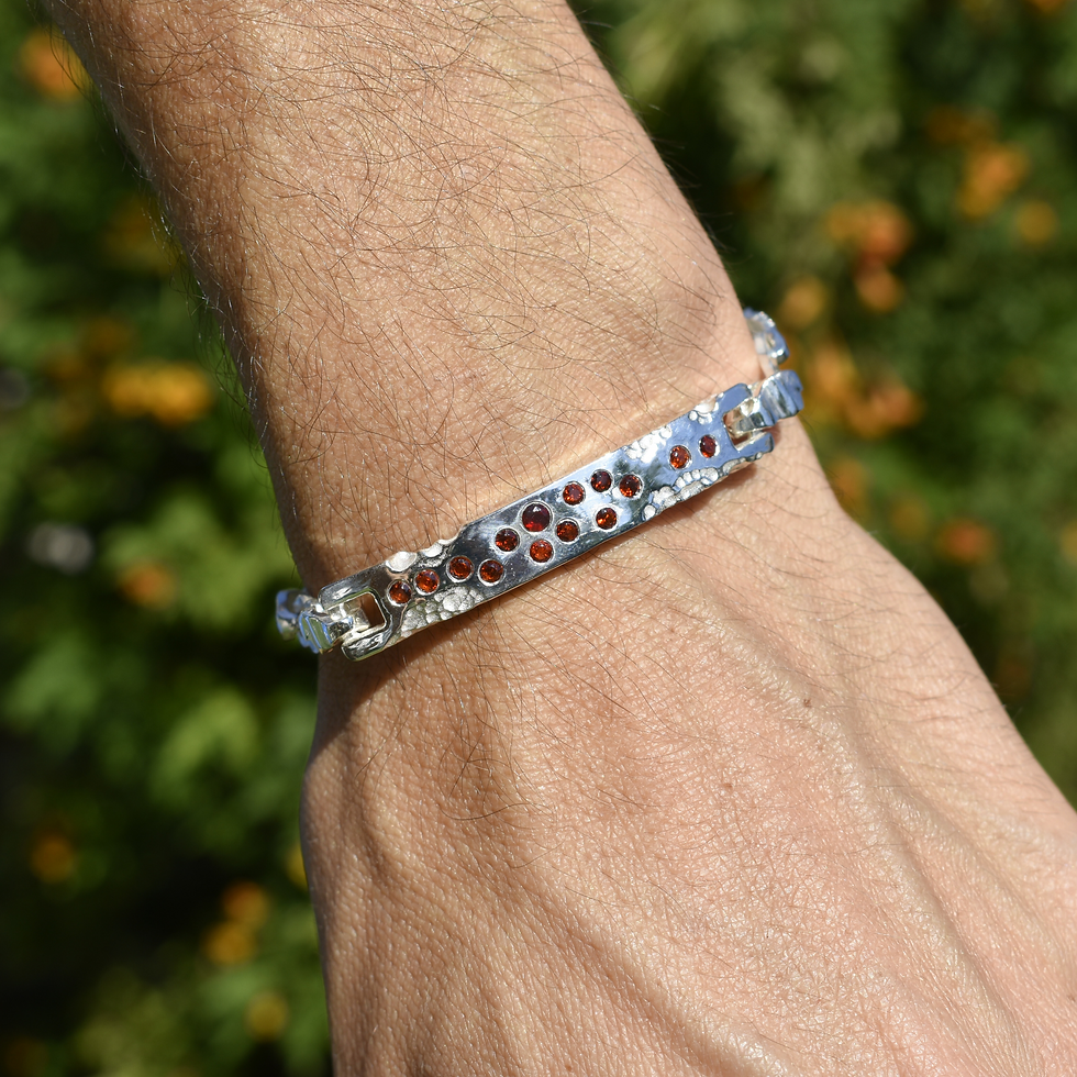 Sterling silver bracelet with hammered finish and garnet stones, bold and unique handmade jewelry.