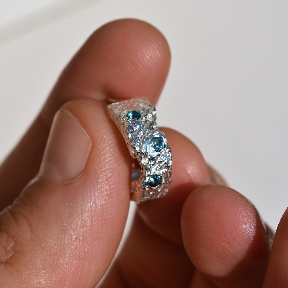 Thumbnail: Close-up photo of handmade sterling silver hoop earring with London Blue Topaz gemstones, featuring a sculptural molten textu
