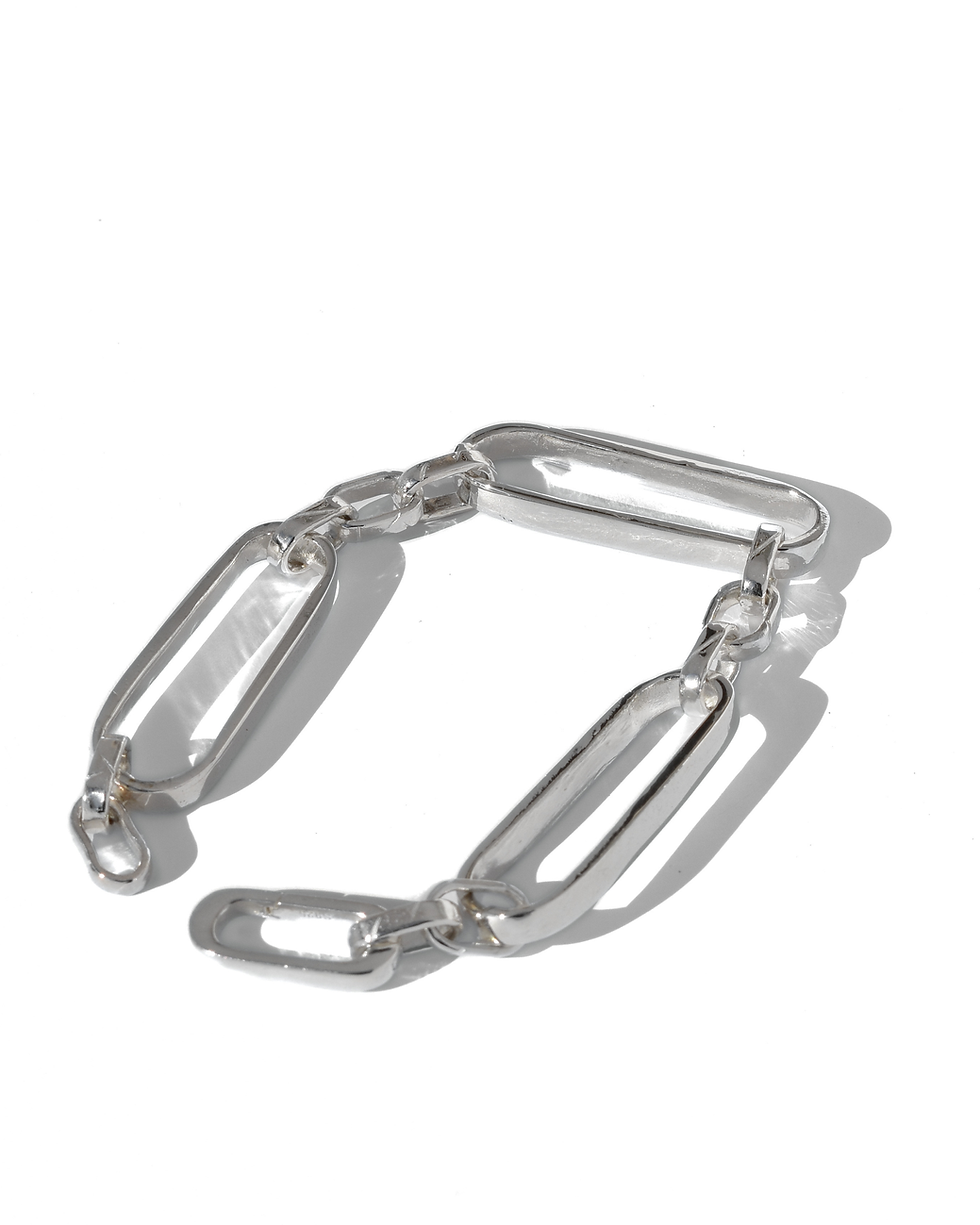 Handmade sterling silver bracelet with elongated chain links, polished finish, worn on wrist in natural light.