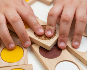 A child's fingers on tactile dominoes. Practicing fine motor & sensory skills.