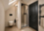 Aménagement d'une salle de bain sous pente avec WC sous rampant, décoration beige et noire réalisée par une architecte d'intérieur en Savoie.