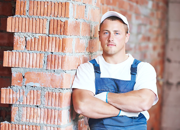 Construction worker. Mason bricklayer standing near brickwall at construction site.jpg