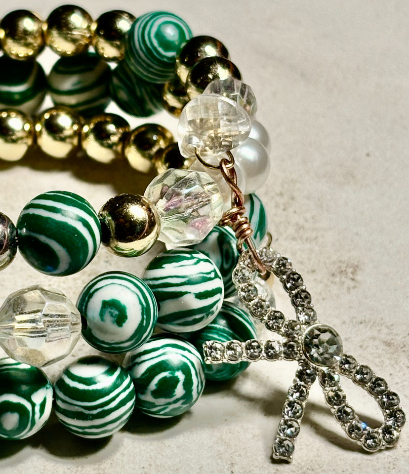 Green patterned wrap bracelet with pearl accents, rhinestone bow detail, and crystal elements in a playful statement design.