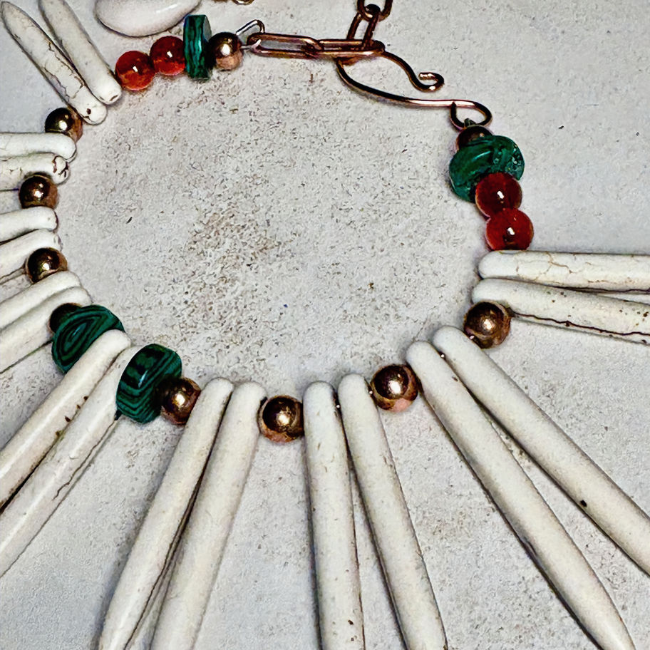 Statement bracelet with spike accents, earthy beads, copper details, and a central kowrie shell design.