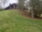 House with a large deck on a grassy hillside