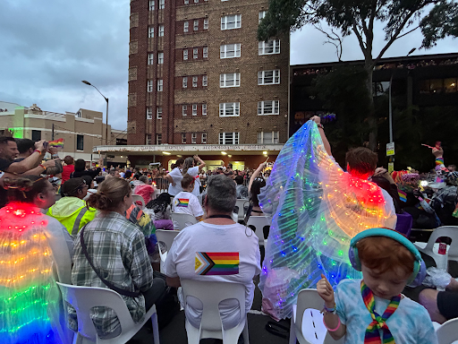 Seated onlookers and people dressed in colourful lights at the Mardi Gras Parade.