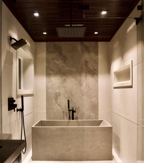 Master bathroom remodel with wet room, the wet room has concrete wall panels, a concrete wall insert or niche for shampoo bottles, a concrete window frame with ledge, a concrete Japanese inspired soaker bathtub, and a wood tongue and groove ceiling made of cypress, there's a concrete vanity top with integral sink in the foreground