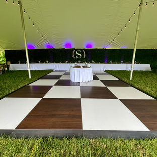 Event/ Wedding Rental Company - Dark Wood Grain & White Dance Floor under tent with boxwood backdrop. banquet tables and linens with bulb lighting
