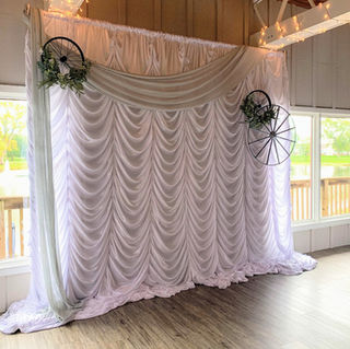 indoor wedding ceremony with white silk rouge draping backdrop for ceremony draping at alter with additional draping and wheel decor 