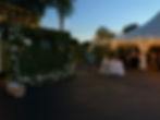 Outdoor Tent Wedding Reception with Strung Twinkle Lights and Acrylic Seating Chart on Boxwood Wall