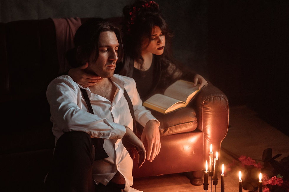 Stanza fiocamente illuminata da candele, con un uomo su una poltrona di cuoio e una donna accanto a lui intenta a leggere un libro aperto; entrambi appaiono pensierosi. Fotografia di Drimage Creative studio di Simona Turano Fotografa e Wedding Planner & Designer