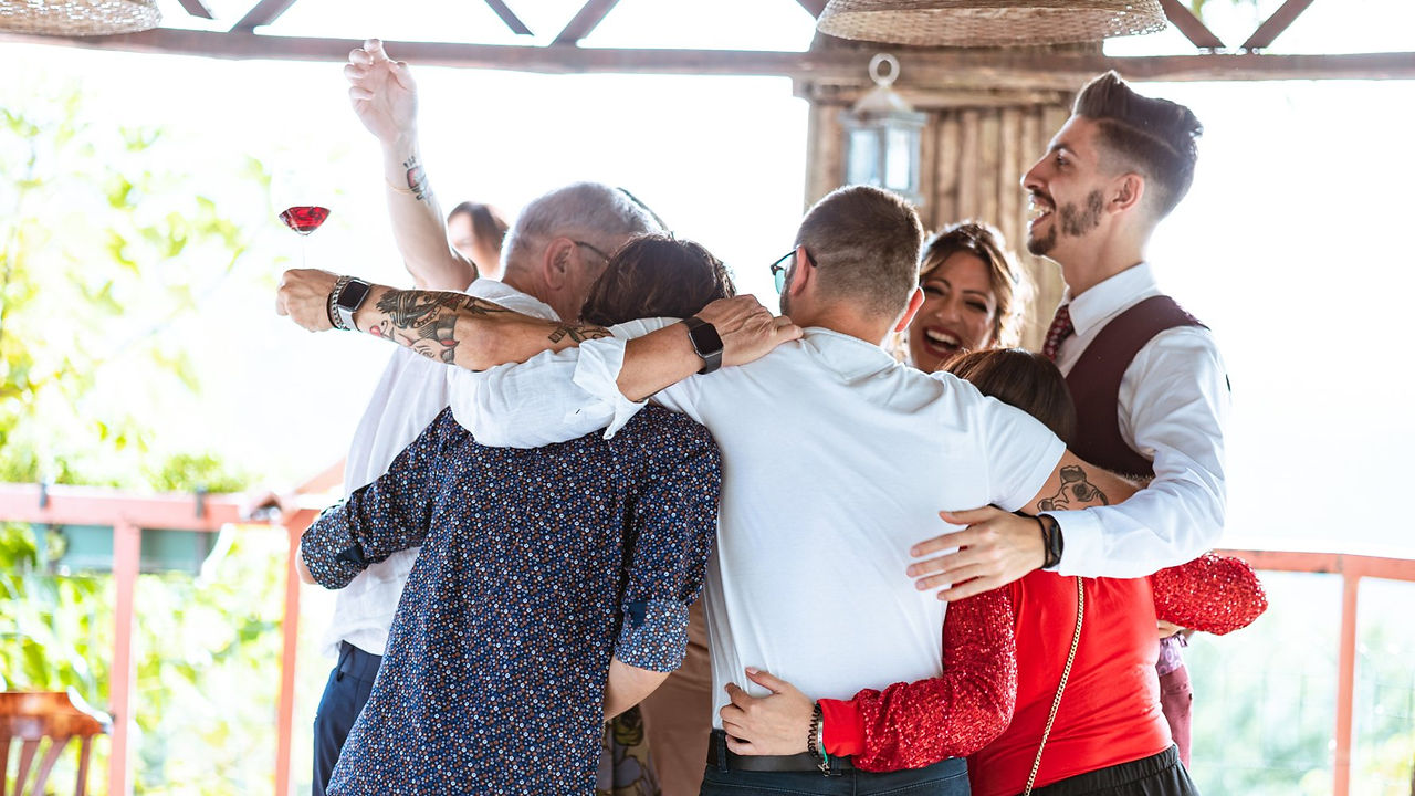 Gruppo amici si abbracciano e festeggiano, foto di coppia senza pose con sorriso.