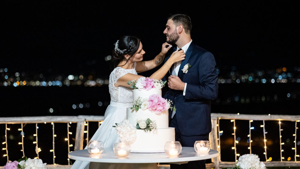 Sposa e sposo tagliano la torta nuziale, matrimonio elegante e romantico, con sfondo notturno.