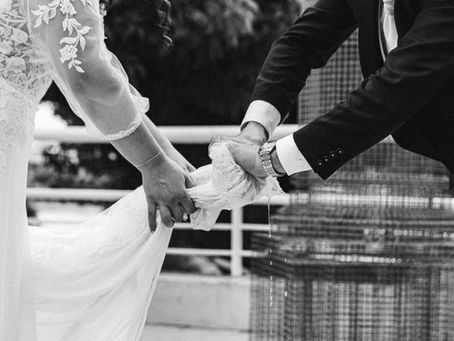 Fotografia di Drimage Creative studio di Simona Turano Fotografa. Gli sposi strizzano insieme un tessuto bagnato. La sposa indossa un abito di pizzo, lo sposo un abito elegante. Il tessuto bagnato gocciola acqua. Ambientazione esterna, in bianco e nero.