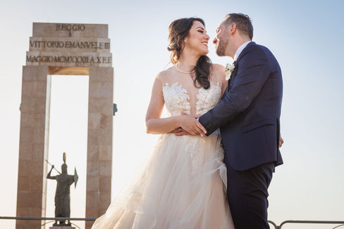 Coppia di sposi sorridono, monumento dietro, Matrimonio verde-mare, raggiante luce solare, Drimage