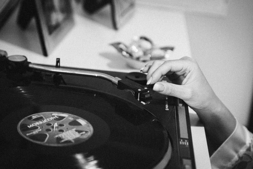 Una mano posiziona l'ago su un vinile nero. Dettaglio musicale vintage