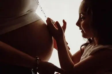 Fotografia di Drimage Creative studio di Simona Turano Fotografa. Bambina accarezza la pancia di donna incinta.