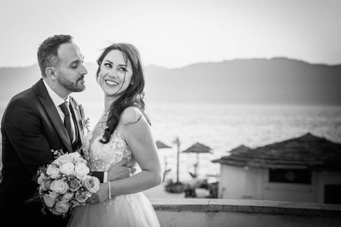 Coppia di sposi sorridente, Matrimonio verde-mare, con sfondo lago e casa sulla spiaggia.
