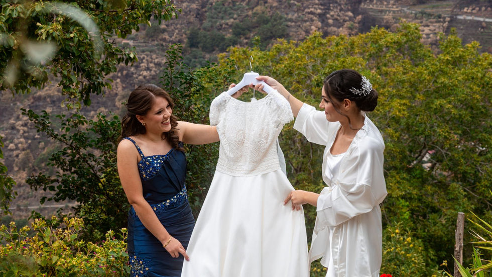 Due donne mostrano abito da sposa. Matrimonio elegante e romantico con verde sfondo.