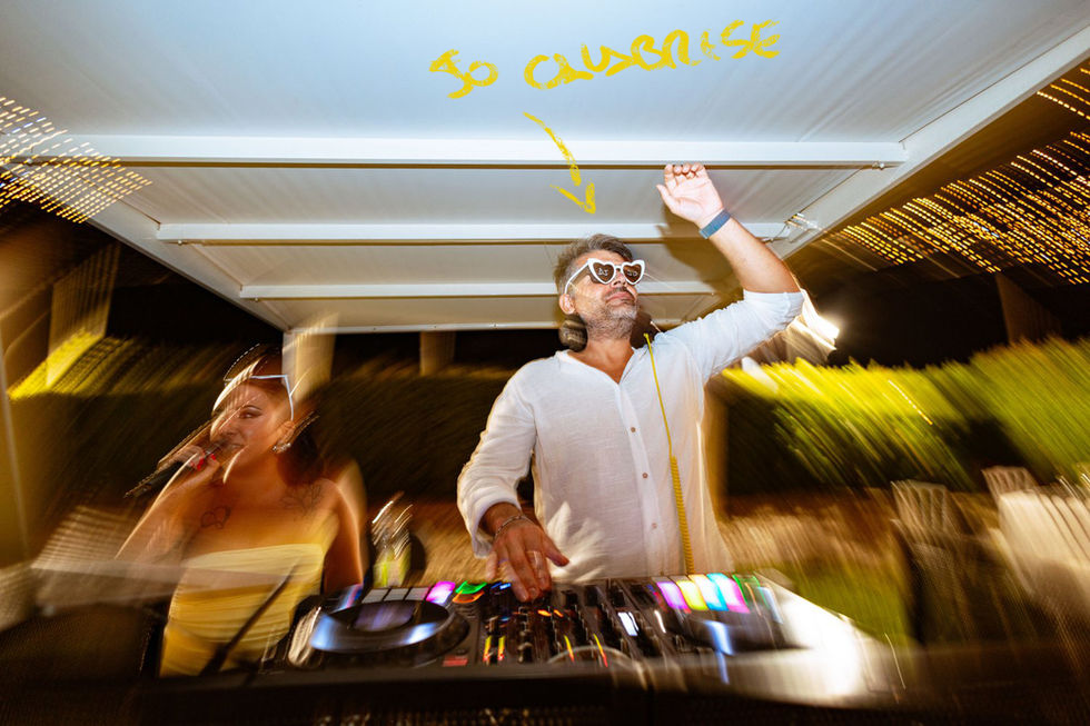 DJ con occhiali da sole, testo "SO CHARMING", anima la festa all'aperto.