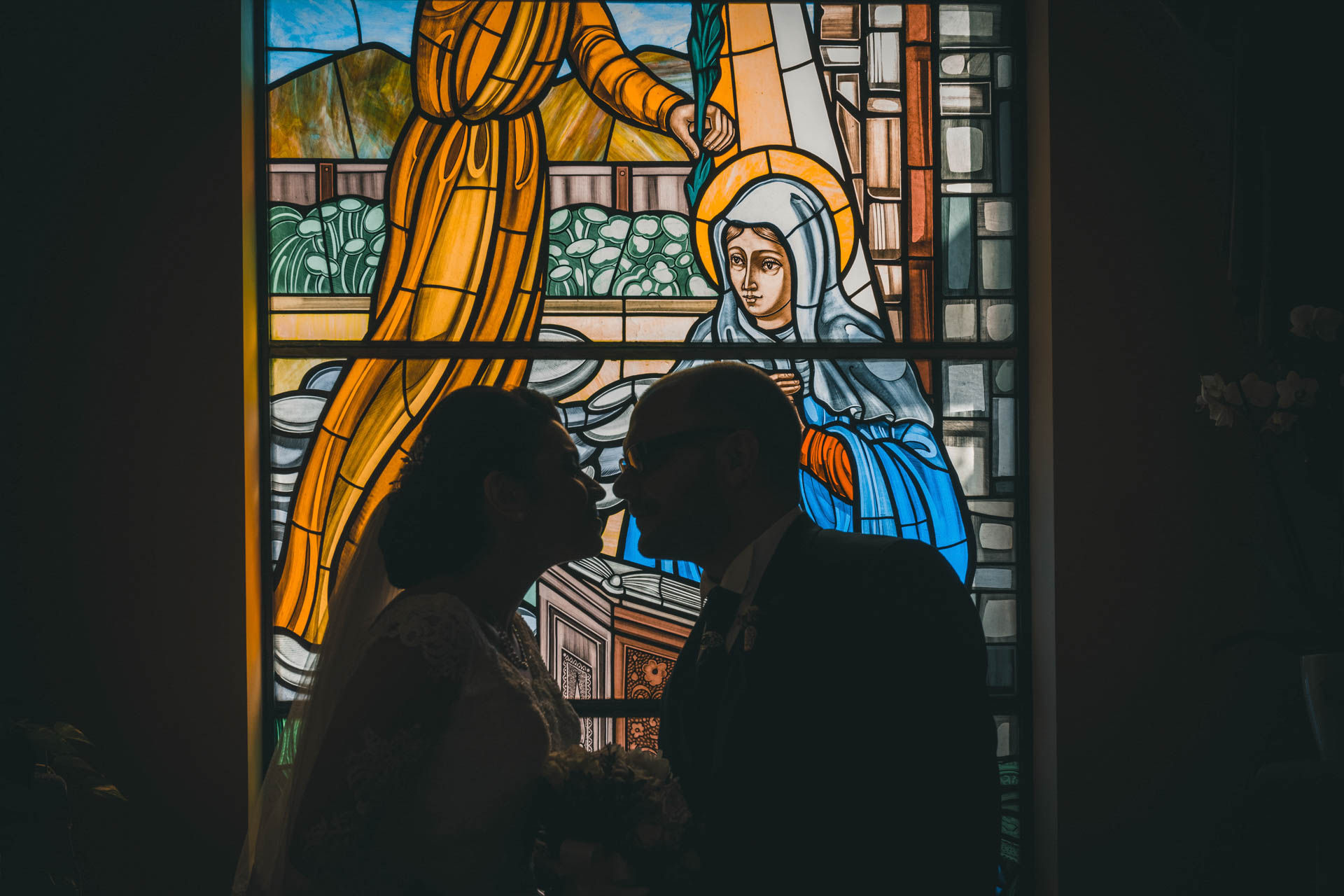 Coppia di sposi si bacia davanti a vetrata, Unconventional wedding, scena romantica, Drimage